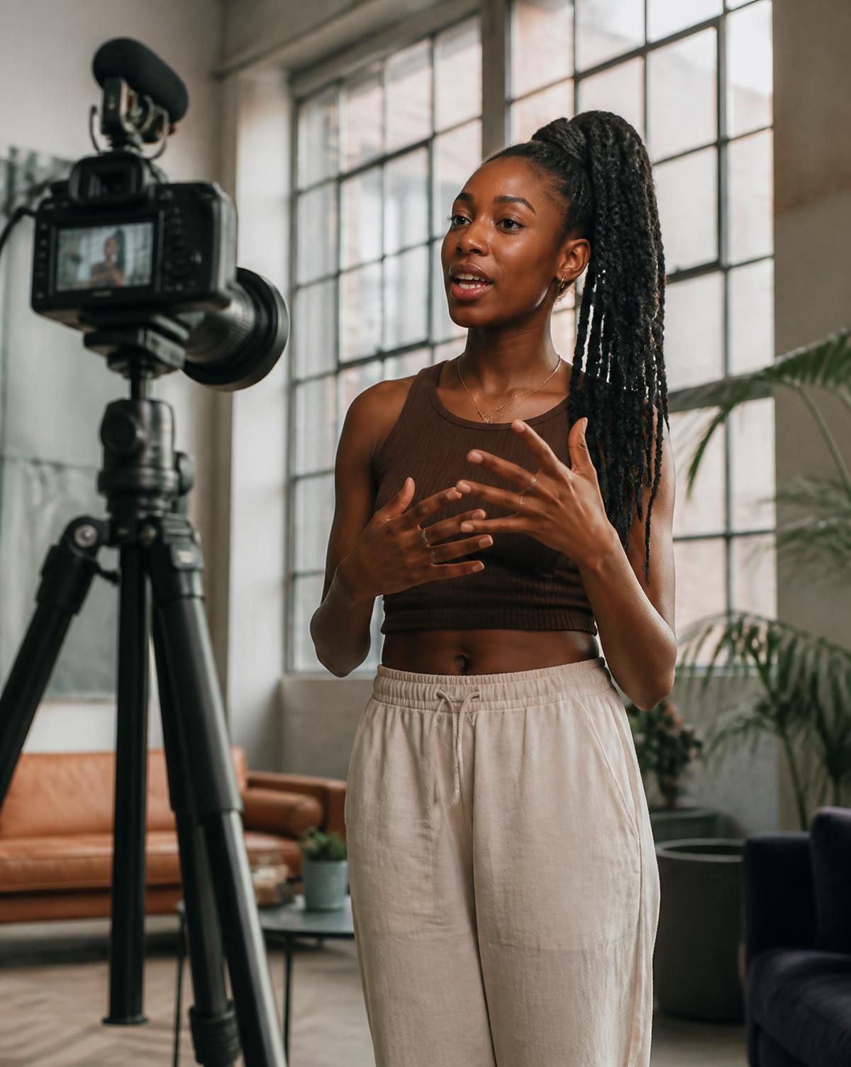 A Black content creator filming to camera in an airy loft studio
